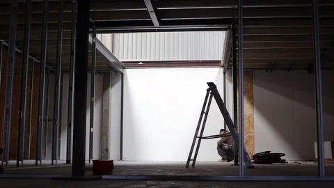 Kneeling builder uses tape measure on construction site Vidéo 78769798
