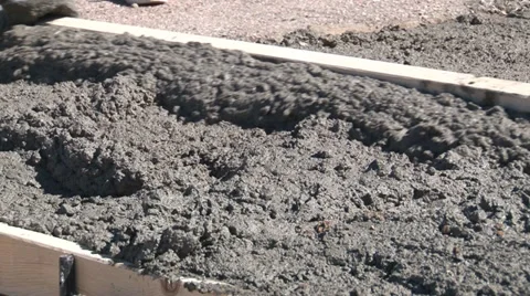 Kneeling cement worker uses screed for initial leveling of wet mix Stock Footage 39908569