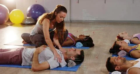 Kneeling instructor guiding man breathing in studio with blue mats and digital 스톡 사진