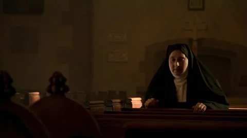 Kneeling nun rising from solitary prayers and leaving nave of church Stock Footage 59249840