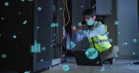 Kneeling tech in hi-vis fixing rack cables in server room, phoning and typing 動画素材 331789742