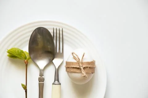 Knife and fork and spoon lie in a white plate on a white background, and next Stock Photos