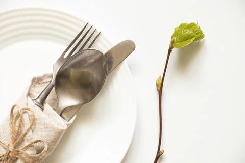 Knife and fork and spoon lie in a white plate on a white background, and next Stock Photos