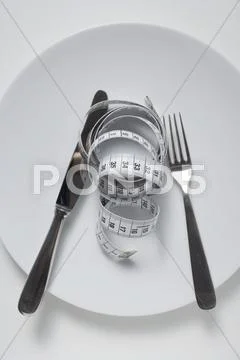 Knife and fork and tape measure on plate Stock Photos