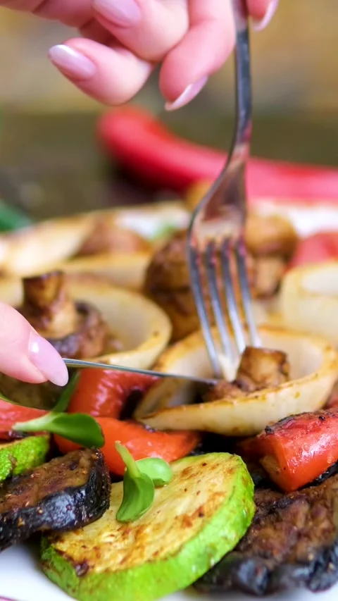 Knife and fork to cut and eat grilled vegetables onion pepper mushrooms set on Stock Footage 323527989