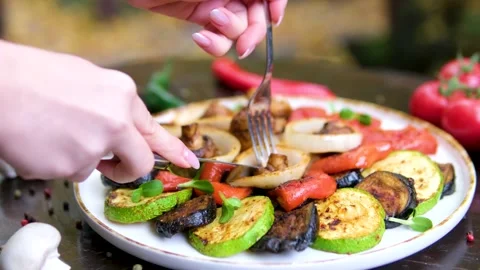 Knife and fork to cut and eat grilled vegetables onion pepper mushrooms set on Stock Footage 323528076
