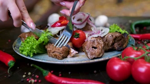 Knife and fork to cut and eat hands are cutting a meat steak on the prep table Stock Footage 323530783