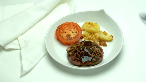 Knife and fork cut a sauteed hamburger with sauce and shallots, Stock Footage 118894530