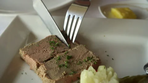 Knife and fork cutting pate goose liver appetizer in French restaurant with p Stock Footage 154797753