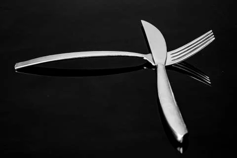 Knife and fork with mirroring only the head with tines in silver metallic Stock Photos