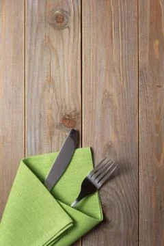 Knife and fork in napkin at rustic wooden background Foto stock