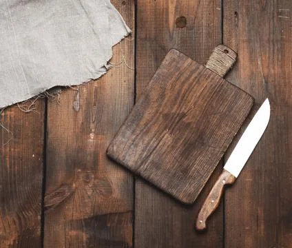 Knife and old brown rectangular wooden kitchen cutting board and gray linen n Foto stock
