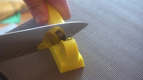 Knife and sharpener for a knife in the hands of man. Manual sharpening of a Stock Footage 75912211
