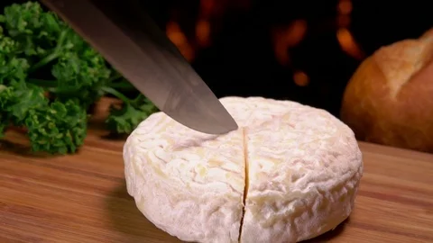 Knife carves a sector of French round cheese Stock Footage
