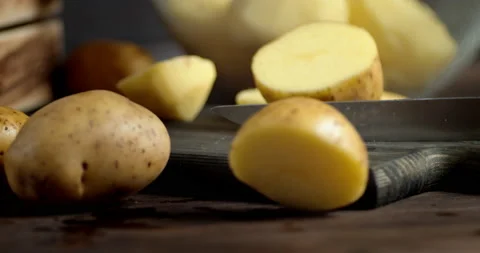 With a knife cut fresh potatoes into two halves. Stock Footage 130211470