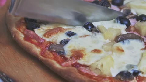 The knife cuts an appetizing pizza with baked cheese and black olives. Cheese Stock Footage 170739319