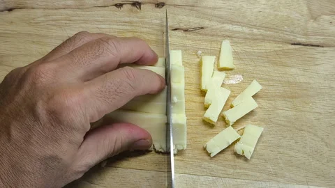 A knife cuts the cheese into simple, small pieces. Stock Footage 318009722