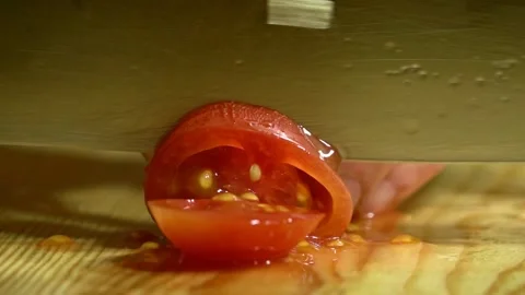 Knife cuts the cherry tomato in kitchen on wooden board. Close up. Stock Footage 231897155