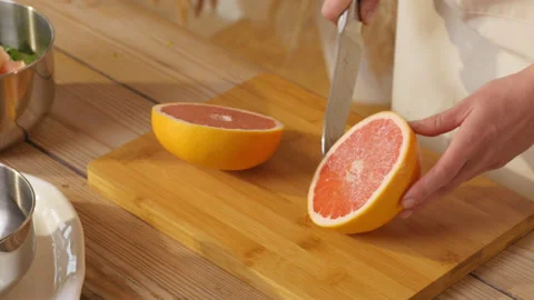 The knife cuts grapefruit. Hands cut fruit. Fruit cut in half. Cooking Stock Footage 162620031