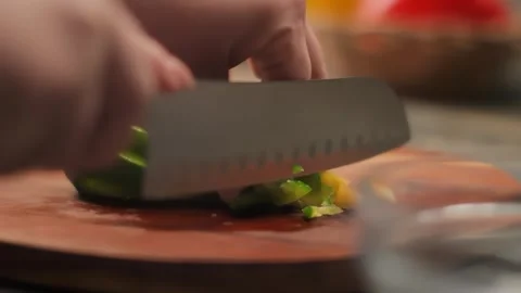 A knife cuts green bell pepper into small pieces on a wooden board. Close-up Stock Footage 314625038