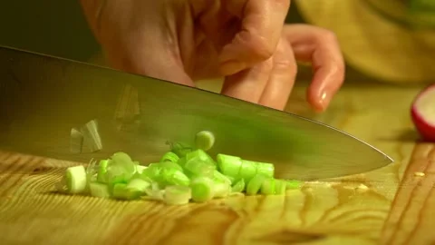 Knife cuts the green onion in kitchen on wooden board. Close up. Stock Footage 231897235