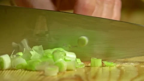 Knife cuts the green onion in kitchen on wooden board. Close up. Stock Footage 231897314