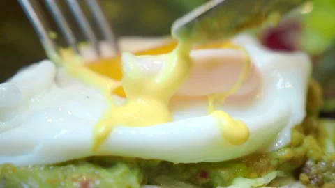 Knife cuts into perfectly poached egg with runny yolk for breakfast on avoc.. 스톡 동영상 331923792