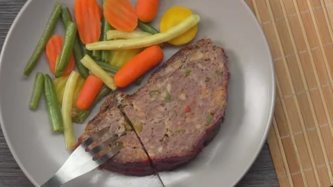 A knife cuts a piece of amethyst cooked juicy meatloaf lying on a gray plate Stock Footage 312469023