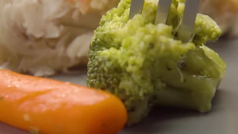 A knife cuts a piece of stewed broccoli Stock Footage 294418364