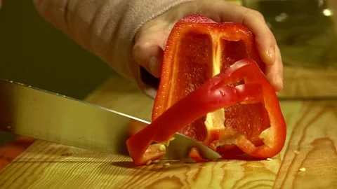 Knife cuts the red pepper in kitchen on wooden board. Close up. Stock Footage 231897245