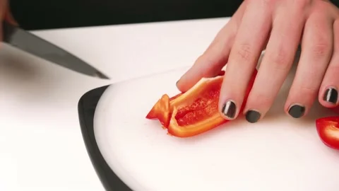 Knife cuts the red pepper. Slicing sweet pepper on a cutting board. Man with Stock-Footage 146908019