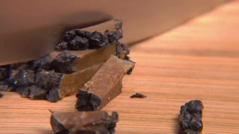 A knife cuts a slice from a black truffle on a wooden board 스톡 동영상 279027993