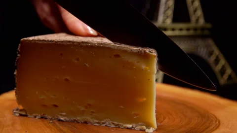 Knife cuts a thin slice of the delicious hard cheese on a wooden board Stock Footage 148875012