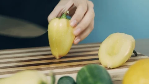 Knife cuts the yellow pepper. Slicing sweet pepper on wooden cutting board. C Stock Footage 112774892