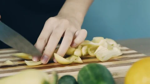 Knife cuts the yellow pepper. Slicing sweet pepper on wooden cutting board. C Stockbeeldmateriaal 112774913