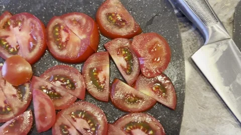 A knife is on a cutting board with a tomato on it Stock Footage 283488324