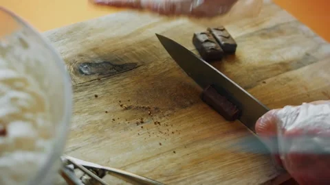 Knife cutting chocolate candy pieces on a wooden board, 4K Stock Footage 341119339