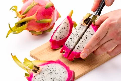 Knife cutting half a pitaya into fruit chips Stock Photos