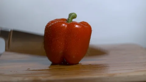 Knife cutting red bell pepper in two halves in slow motion Stock Footage 100008145
