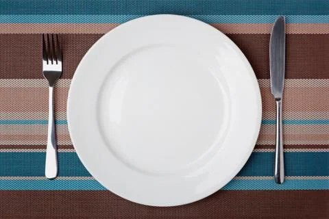 Knife, fork and plate on table. Stock Photos