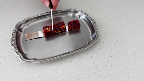 Knife Meets Candy: Slicing Nutty Red Treats on Ornate Tray Video stock 316581392