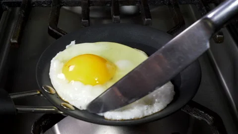 Knife moving an egg which is frying in a very small pan. Stock-Footage 141791252