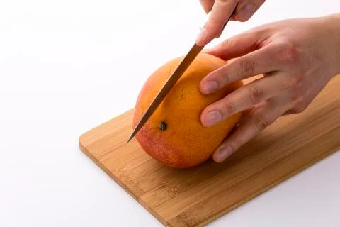 Knife in position for a first cut through a mango Stock Photos