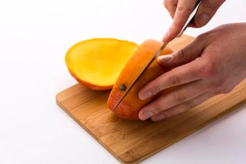 Knife positioned for a second cut through a mango Stock Photos