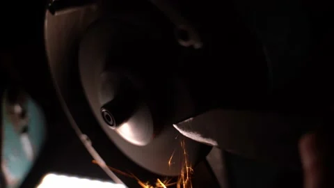 The knife is sharpened with an abrasive wheel on a grinder in the dark Stock Footage 231094565