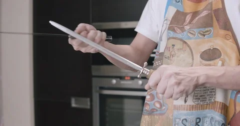 Knife sharpening by chef in the home interior at the kitchen Stockbeeldmateriaal 123982984