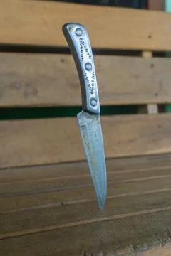 A knife with a silver handle, embedded upright into a wooden surface Stock-Fotos
