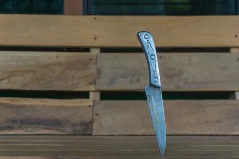 A knife with a silver handle, embedded upright into a wooden surface 库存照片