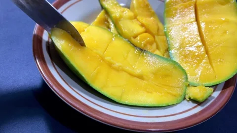 Knife slices mango on a ceramic plate Stock Footage 346710589
