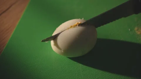 Knife slices whole boiled egg on green cutting board Stock Footage 312767185